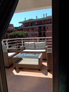 a patio with a couch and chairs on a balcony at E&C Suites Roma in Lido di Ostia