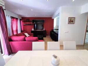 uma sala de estar com um sofá vermelho e cadeiras brancas em T-3 Frente Mar lote19- Casas & Papeis em Armação de Pêra