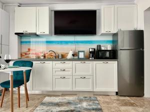 eine Küche mit weißen Schränken und einem Edelstahlkühlschrank in der Unterkunft Bakuba - Studio pe plaja cu vedere la mare & loc parcare gratis in Mamaia Nord – Năvodari + 22 Fotos