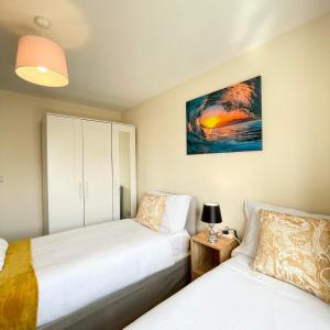 a bedroom with two beds and a painting on the wall at Karuna House in Norwich