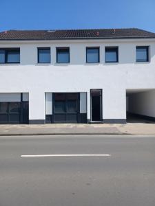 a white building with black doors and a street at kleines boardinghouse in Nordwalde