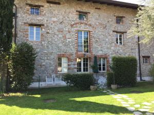 une maison en pierre avec 2 chaises blanches dans la cour dans l'établissement Apartment Magalita, à Udine