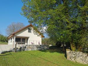 a white house with a tree and a stone wall at La Maison du Colombier in Le Fied