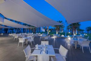 a restaurant with white tables and white chairs at Tour Khalef in Sousse