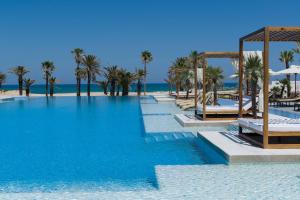 - une grande piscine à côté d'une plage bordée de palmiers dans l'établissement Jaz Tour Khalef, à Sousse
