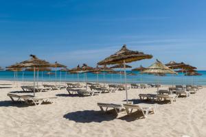 eine Gruppe von Stühlen und Sonnenschirmen am Strand in der Unterkunft Jaz Tour Khalef in Sousse