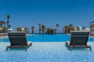 two chairs sitting in the middle of a swimming pool at Jaz Tour Khalef in Sousse