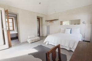 a white bedroom with a bed and a chair at Relax in Borgosesia