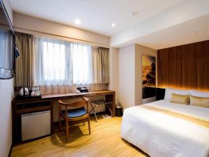 Pokój hotelowy z łóżkiem i biurkiem w obiekcie City Hotel w Tajpej