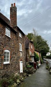 uma velha casa de tijolos com uma porta branca numa rua em 4 St Richard’s Cottages em Fittleworth