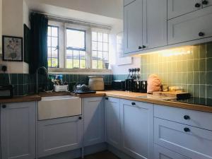 uma cozinha com armários brancos e um lavatório em Abbot's Wing em Stroud