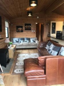 a living room with leather couches and a stove at Lomond Lodge in Rowardennan