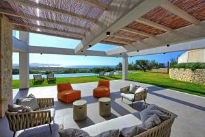 a patio with couches and chairs under a roof at Luxury Villa Ebellina by PosarelliVillas in Acharavi