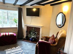 a living room with a fireplace and a tv on the wall at 4 St Richard’s Cottages in Fittleworth