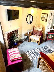 a living room with a fireplace and a chair and a mirror at 4 St Richard’s Cottages in Fittleworth