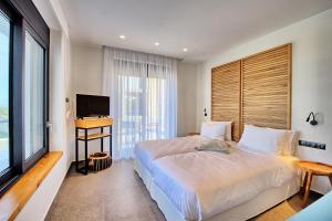 a bedroom with a bed and a desk and a television at Luxury Villa Ebellina by PosarelliVillas in Acharavi +38 photos
