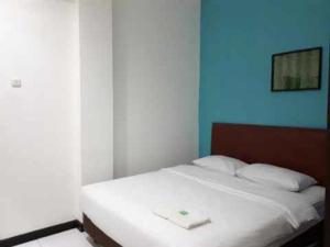 Una cama blanca en una habitación con una pared azul. en RedDoorz at Hotel Rumberpon Sorong, en Sorong