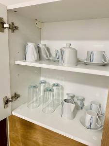a white shelf with glass vases and cups on it at Apartment Loser im Zentrum in Bad Ischl