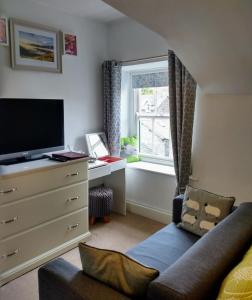 a living room with a couch and a tv and a window at The Lakes B and B in Ambleside