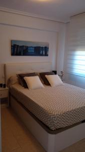 Cama en habitación blanca con 2 almohadas en PRIMERA LINEA DE PLAYA, VISTAS AL MAr, en Benicàssim