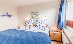 a bedroom with a blue and white bed and a window at Terrassen-Fewo-Heimathaven-direkt-am-Ostseestrand in Kronsgaard +43 photos