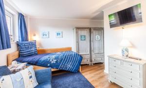 a bedroom with a bed and a tv in it at Terrassen-Fewo-Heimathaven-direkt-am-Ostseestrand in Kronsgaard