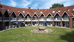 a large brick building with a yard in front of it at Terrassen-Fewo-Heimathaven-direkt-am-Ostseestrand in Kronsgaard