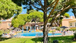 a pool at a resort with people sitting around it at Bicos 303 - Shared Pool - 6 Guests - Albufeira in Albufeira +20 photos