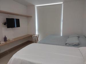 a bedroom with a white bed and a flat screen tv at Edificio Reserva del Mar, Paya Salguero , Santa marta in Gaira