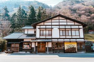 a building on the side of a street with a mountain at Guesthouse Shimashima in Matsumoto