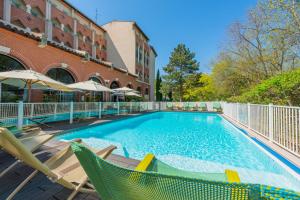 a swimming pool with chairs and a building at Novotel Toulouse Centre Compans Caffarelli in Toulouse