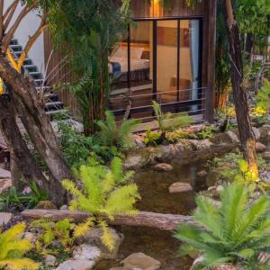 un jardin en face d'une maison avec un étang dans l'établissement Tolopoti Hotel&Resort, à U Thong