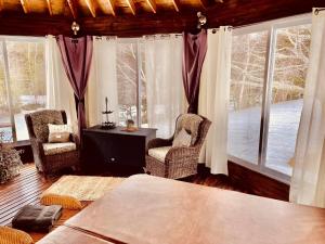 a room with two chairs and a table and windows at Forest & Lake PEI Bed & Breakfast in Murray Harbour