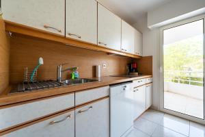 a kitchen with white cabinets and a sink and a window at Le Drive in Saint-Raphaël