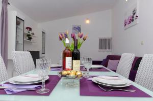 a dining room table with a bottle of wine and flowers at Apartment Zvonimir in Nečujam