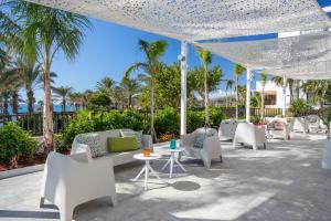 a patio with white chairs and tables and palm trees at Barceló Cabo de Gata in Retamar