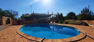a large blue swimming pool in the yard of a house at Rural Peace in the Algarve - Private Room with kitchenette and bathroom in Aldeia dos Matos