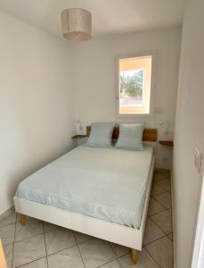 ein Schlafzimmer mit einem Bett mit blauen Kissen und einem Fenster in der Unterkunft Les locations Cinaureva « Village de la mer » in La Londe-les-Maures