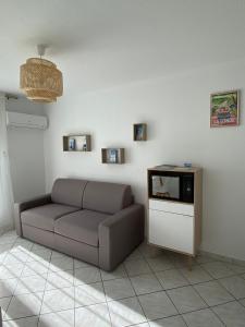 ein Wohnzimmer mit einem Sofa und einem TV in der Unterkunft Les locations Cinaureva « Village de la mer » in La Londe-les-Maures