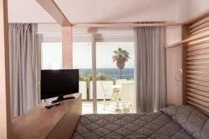 a living room with a television and a view of the ocean at Hotel Villaggio Stromboli in Santa Domenica