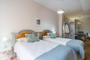two beds in a bedroom with white and blue at Apartamentos RG Suites Sierpes 54 in Seville