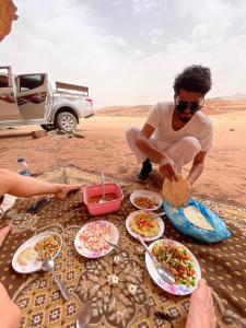 Ein Mann isst in der Wüste an einem Tisch. in der Unterkunft Wadi Rum Desert Adventures in Wadi Rum