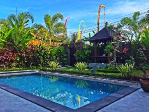 a swimming pool in a garden with plants at Villa D'Uma in Ubud