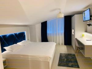 Un dormitorio con una cama y un escritorio y una ventana. en Valea Putnei Residence- Rooms for rent, en Valea Putnei