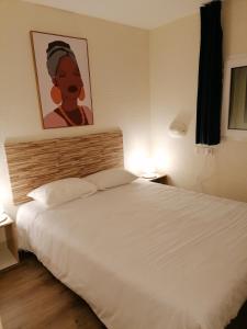 1 dormitorio con 1 cama blanca y una pintura en la pared en Cit'Hotel Saxotel Chalon-sur-Saône Nord, en Champforgeuil