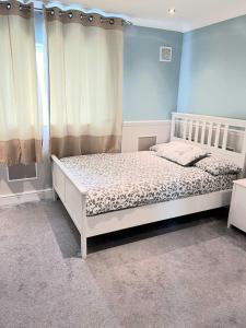 a bedroom with a white bed with blue walls and curtains at Specious 3bed property with parking & large garden in Aveley