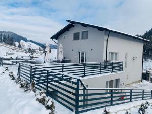 a white house with a fence in the snow at Valea Putnei Residence- Rooms for rent in Valea Putnei