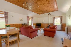 una sala de estar con sillas rojas y techo de madera. en Doonans Cottage, en Maybole