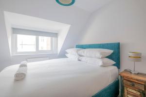 a white bed with white pillows and a window at 3-bedroom apartment in the heart of Brighton's Lanes in Brighton & Hove