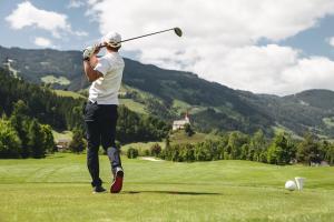 a man swinging a golf club on a golf course at H21 - Modernes Ferienhaus 145qm, 4SZ, Wellnessbereich mit Sauna und Dachterrasse mit Panoramablick, Kühlen und Heizen mit Geothermie in Fügen